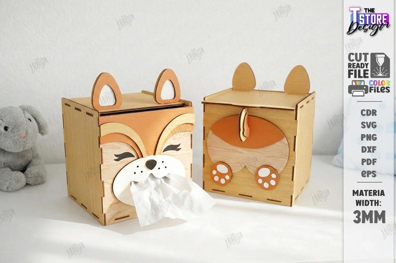May include: Two wooden tissue box holders, one with a fox face design and the other with a fox tail and paw design. The boxes are made of light brown wood with orange and white accents. The text on the side says "CUT READY FILE" and "MATERIA WIDTH: 3MM".