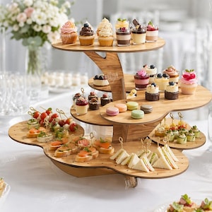 May include: A multi-tiered wooden dessert stand displaying various miniature desserts, including cupcakes, pastries, and finger sandwiches. The stand is made of light-colored wood and is filled with an assortment of treats. The text "CUT READY FILE DIGITAL DOWNLOAD" is visible.