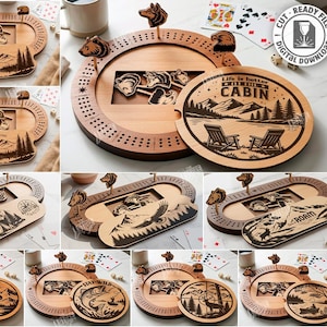 May include: A selection of wooden cribbage boards and coasters with laser-cut designs. The boards feature mountain, bear, and wildlife themes. The coasters have the text "Life is better in the cabin" and other outdoor scenes. Includes digital cut files.