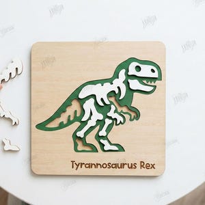 K&ouml;nnte beinhalten: Holzpuzzle Tyrannosaurus Rex mit gr&uuml;nem und wei&szlig;em Dinosaurierskelett-Design. Die Puzzleteile werden auf einer hellbraunen Holzbasis zusammengesetzt. Der Text "Tyrannosaurus Rex" befindet sich am unteren Rand des Puzzles.