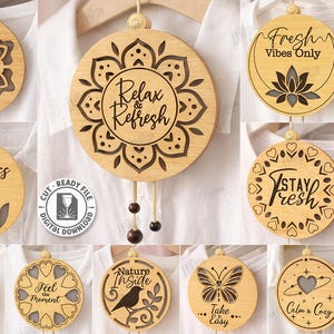 May include: A collection of ten wooden laser-cut designs, each with a unique inspirational message. The round ornaments feature various designs, including floral patterns, butterflies, and text like "Breathe Easy" and "Relax & Refresh."