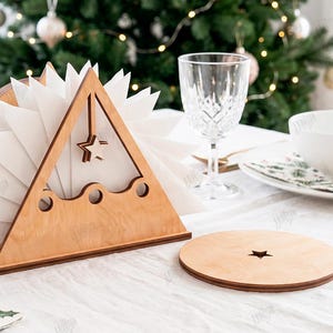 May include: A triangular wooden napkin holder with a star cutout and three circular holes, holding white napkins. Beside it sits a round wooden coaster with a small star cutout. The material width is clearly labeled as 3mm on the side.