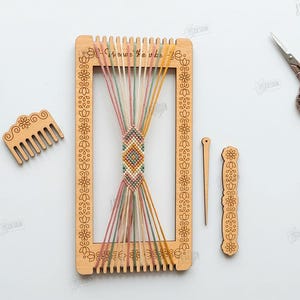 Op de afbeelding: Een houten weefgetouw met kleurrijke draden, een kleine kam en andere gereedschappen. Het weefgetouw heeft een bloemenpatroon en de tekst "Mawi Toube". De afbeelding bevat ook een schaar en tekst met de tekst "Cut Ready File Digital Download".