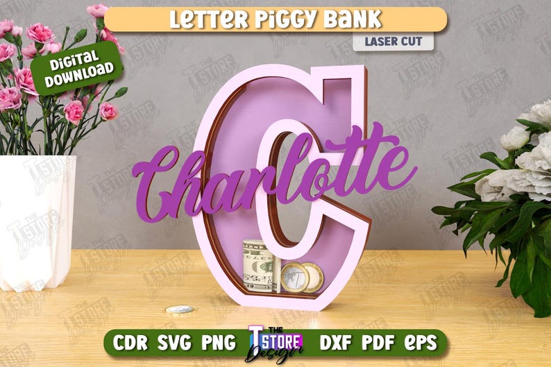 Puede incluir: Una hucha de madera con forma de letra "C" en color lila claro, con el nombre "Charlotte" en cursiva. El banco contiene dinero y monedas. Las palabras "Letter Piggy Bank" y "Laser Cut" son visibles.