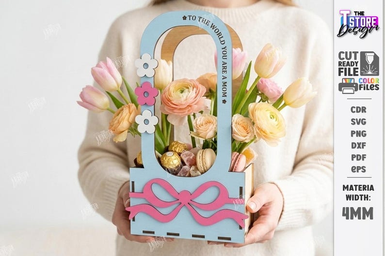 May include: A wooden floral arrangement with a light blue frame and a pink bow. The arrangement includes pink and yellow flowers, chocolates, and macarons. The text "TO THE WORLD YOU ARE A MOM" is on the frame.