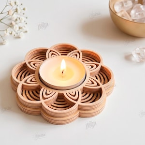 May include: A light-colored wooden tea light candle holder featuring a layered, flower-shaped design with concentric petal cutouts. A single lit tea light candle sits in the center. The image includes text: THE STORE DESIGN, CUT READY FILE DIGITAL DOWNLOAD, CDR, SVG, PNG, DXF, PDF, EPS, COMPATIBLE WITH ANY MATERIAL THICKNESS.