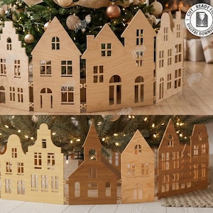 May include: A wooden Christmas tree surround with a village design. The laser-cut panels depict various house shapes with windows and doors. The surround is made of light brown wood and is designed to encircle a Christmas tree. The image also includes text that says "CUT READY FILE DIGITAL DOWNLOAD".