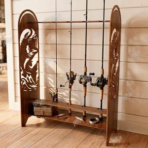 May include: A wooden fishing rod rack with decorative side panels. The rack holds several fishing rods and reels, along with a tackle box and fishing lures. The text on the side says "CUT READY FILE DIGITAL DOWNLOAD".