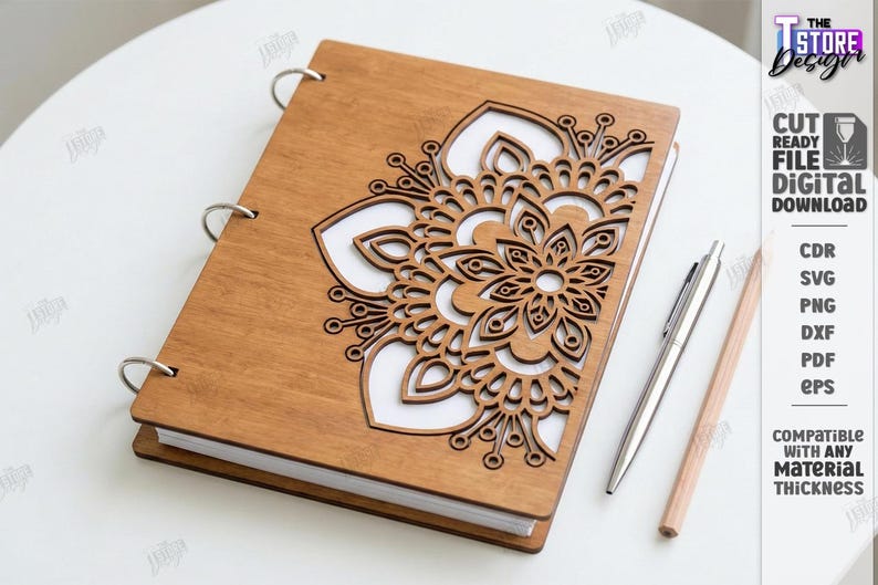 May include: A wooden notebook with a laser-cut floral design on the cover. The notebook is open, revealing white pages. A silver pen and a pencil are placed beside the notebook. The notebook is a digital download.