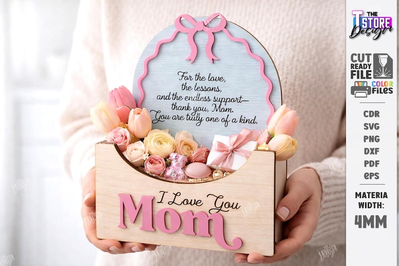 May include: A wooden Mother's Day gift box with the words "I Love You Mom" in pink. The box contains flowers and a small gift. A light blue sign with a pink border and a message is behind the flowers.