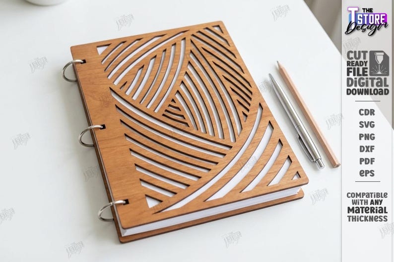 May include: A wooden notebook with a geometric design cut into the cover. The cover is light brown and has a pattern of curved lines. The notebook is open, revealing white pages. A pen and pencil are next to the notebook.