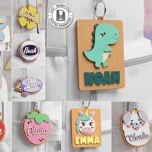 May include: A collection of laser-cut wooden name tags in various shapes, including a butterfly, flower, dinosaur, bunny, apple, strawberry, rocket, astronaut, unicorn, and dog. Each tag features a name in a contrasting color.
