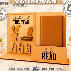 Puede incluir: Seguimiento de libros de madera con el texto "Books read THIS YEAR" y "to be READ". Cuenta con espacio para un libro, una planta y un calendario con los n&uacute;meros 093. Dise&ntilde;o cortado con l&aacute;ser.