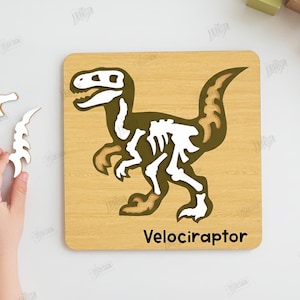 K&ouml;nnte beinhalten: Holzpuzzle mit einem Dinosaurierskelett-Design. Das Puzzle zeigt einen Velociraptor mit seinem Namen unten. Enth&auml;lt separate Teile f&uuml;r die Montage. Das Puzzle ist aus Holz.