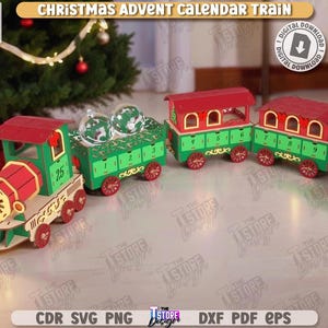 May include: A wooden Christmas advent calendar train with red and green carriages. The train features a locomotive and several cars, each with a numbered door. The train is decorated with festive details and is set against a Christmas tree background.