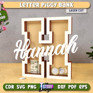 Puede incluir: Una hucha de madera con forma de letra "H" con el nombre "Hannah" en escritura blanca. El banco contiene billetes enrollados y monedas. Las palabras "Letter Piggy Bank" y "Laser Cut" est&aacute;n en la parte superior.
