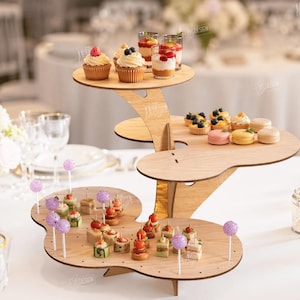 May include: A wooden tiered dessert stand with three levels, holding cupcakes, mini tarts, macarons, and other small treats. The stand is made of light-colored wood and is decorated with various desserts. The text "CUT READY FILE DIGITAL DOWNLOAD" is visible.