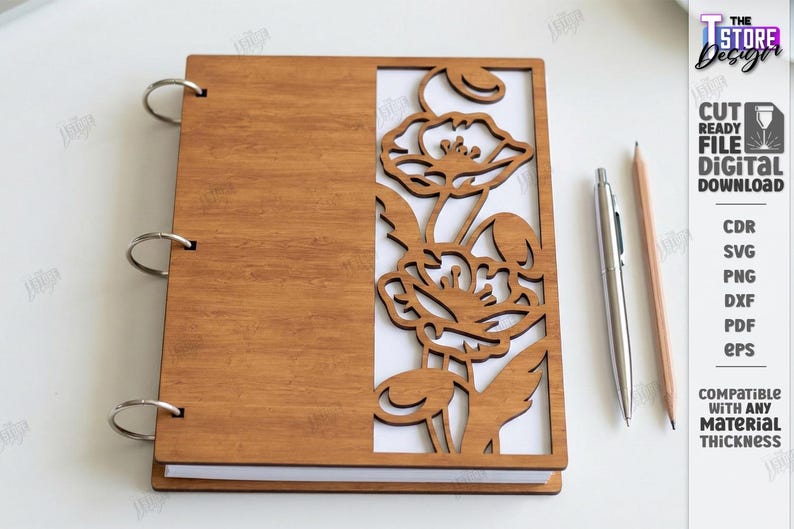 May include: A wooden notebook with a laser-cut floral design on the cover. The notebook is held together with silver rings. A silver pen and a pencil are next to the notebook. The text on the right says "CUT READY FILE DIGITAL DOWNLOAD".
