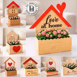Puede incluir: Una colección de maceteros de madera con forma de casa y tejados rojos, cada uno con rosas rosas. Algunos diseños presentan corazones, la palabra "Love" o frases como "Love at home". La imagen incluye un gráfico de diseño "Laser Cut".