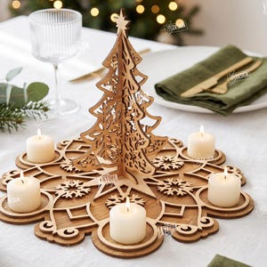 Op de afbeelding: Een lasergesneden houten kerstboom-tafelstuk met een basis met sneeuwvlokpatroon en vier ronde kaarsenhouders. Het ontwerp bevat een ster als piek en vier witte votiefkaarsen. De materiaaldikte is in de tekst aangegeven als 3mm.