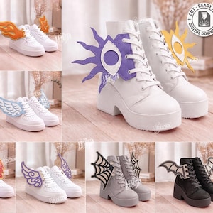 May include: A digital collection of 10 laser cut designs for shoe accessories, featuring various shapes like wings, flames, eyes, and spider webs. These decorative attachments are shown displayed on white, pink, blue, gray, and black boots and sneakers.