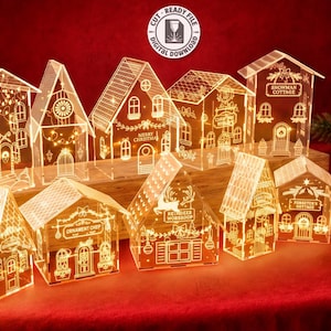 May include: A collection of ten laser-cut acrylic house structures featuring intricate holiday-themed engravings, illuminated with warm internal lighting. The designs include various architectural styles with festive details, intended for 3mm material thickness.