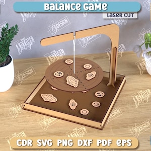 Può includere: Un gioco di equilibrio in legno tagliato al laser con una piattaforma circolare e varie forme. Il testo "Balance Game" è visibile. L'immagine mostra anche piante in vasi bianchi.