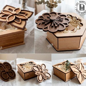 Puede incluir: Cajas de madera cortadas con láser con tapas en forma de flor. Las cajas son de color marrón claro con detalles florales en marrón oscuro. La imagen muestra cinco diseños diferentes, con el texto "CUT READY FILE DIGITAL DOWNLOAD" y "5 DESIGNS".