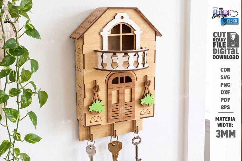 May include: A light brown wooden wall-mounted key holder shaped like a house with a white balcony, a central door, and two decorative hanging plant cutouts. Three metal hooks extend from the bottom, each holding a metal key. Text includes 3MM.