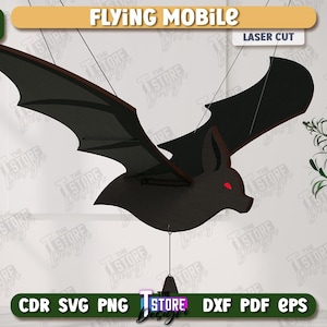 Puede incluir: Móvil de murciélago negro cortado con láser con ojos rojos y bordes de alas marrones, suspendido por cuerdas. Las palabras "FLYING MOBILE" y "LASER CUT" se muestran encima del murciélago.