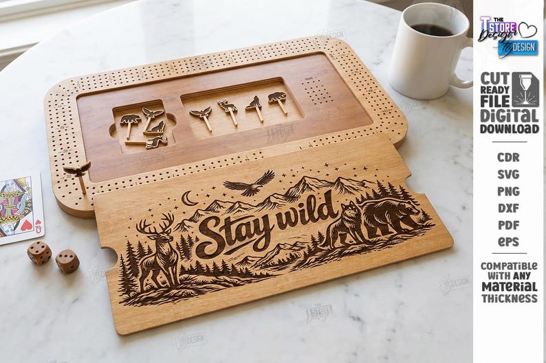 K&ouml;nnte beinhalten: Cribbage-Brett aus Holz mit einem "Stay Wild" Design. Das Brett zeigt eine detaillierte Berg- und Wildtierszene, darunter ein Hirsch, ein B&auml;r und ein Wolf. Enth&auml;lt Stifte und einen separaten Deckel. Eine Tasse Kaffee, W&uuml;rfel und eine Spielkarte sind ebenfalls sichtbar.