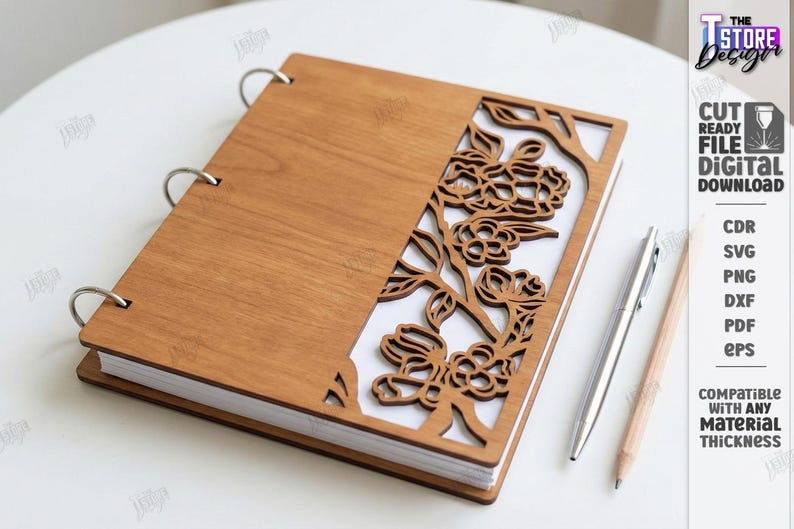 May include: A wooden notebook with a floral cut-out design on the cover. The notebook is held together with silver rings. A silver pen and a wooden pencil are placed beside the notebook. The text "CUT READY FILE DIGITAL DOWNLOAD" is visible.