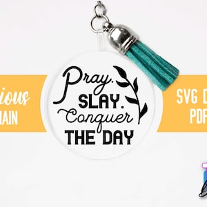 Pu&ograve; includere: Un portachiavi rotondo e trasparente con una scritta nera che recita "Pray. Slay. Conquer The Day." Il portachiavi ha un pon pon turchese.