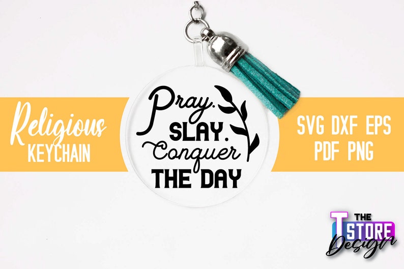 Pu&ograve; includere: Un portachiavi rotondo e trasparente con una scritta nera che recita "Pray. Slay. Conquer The Day." Il portachiavi ha un pon pon turchese.