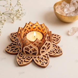 May include: A laser-cut wooden lotus flower candle holder with intricate petal cutouts, holding a single lit tea light candle. The design features layered wooden components and is presented as a digital download file for cutting machines.