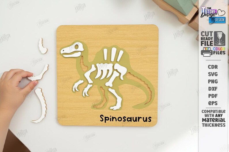 K&ouml;nnte beinhalten: Holzpuzzle eines Spinosaurus-Dinosauriers mit wei&szlig;en Knochen und einem gr&uuml;nen K&ouml;rper. Die Puzzleteile sind getrennt, mit dem Wort "Spinosaurus" auf der Basis. Design-Dateiformate sind ebenfalls enthalten.