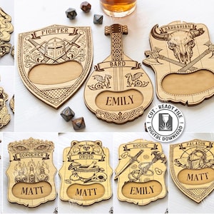 K&ouml;nnte beinhalten: Eine Sammlung von zehn lasergeschnittenen Holzdesigns, die jeweils eine Fantasy-Klasse wie Zauberer, K&auml;mpfer und Barde darstellen. Die Designs beinhalten personalisierte Namensausschnitte und aufwendige Details.