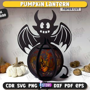 Może przedstawiać: Czarna papierowa latarnia w kształcie dyni z motywem diabelskiego nietoperza. Latarnia ma świecące wnętrze z motywem Halloween. Widoczne są słowa "PUMPKIN LANTERN" i "DIGITAL DOWNLOAD".