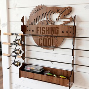 May include: A wooden fishing rod rack with a fish silhouette and the words "FISHING is for the COOL" engraved on it. The rack holds three fishing rods and has a lower shelf for tackle. The material width is 6mm.