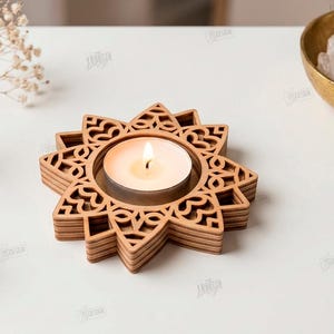 May include: A light brown wooden tea light candle holder with a star-shaped, laser-cut geometric pattern. The holder features a central circular opening containing a lit white tea light candle. Text on the right reads: CUT READY FILE DIGITAL DOWNLOAD CDR SVG PNG DXF PDF EPS COMPATIBLE WITH ANY MATERIAL THICKNESS.