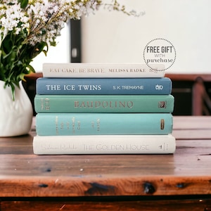 May include: A stack of five books with blue and green covers. The titles of the books are "Eat Cake. Be Brave", "The Ice Twins", "Baudolino", "Somewhere Safe with Somebody Good", and "The Golden House".