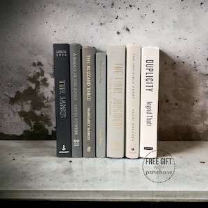 May include: A shelf with a collection of books with different colored spines. The books are titled "The Janes", "A Shout in the Ruins", "The Buzzard Table", "Hair of the Dog", "The Final Judgment", "The Invisible Front", and "Duplicity".
