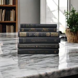 May include: A stack of black hardcover books with gold lettering on a white marble surface. The titles include "They Call Us Dead Men", "Spirit of the Season", "The Rise of Shiva", "Quicksand", "Glory over Everything", and "The Secret Corps".