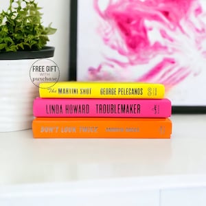 May include: A stack of three paperback books with bright yellow, pink, and orange covers. The titles are "The Martini Shot", "Troublemaker", and "Don't Look Twice".