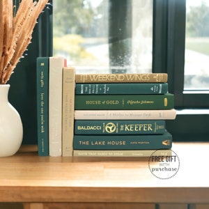 May include: A stack of ten books with green and cream covers. The books are arranged in a vertical stack on a wooden surface. The titles of the books are visible, including "Weekend Wings", "House of Gold", "The Keeper", and "The Lake House".