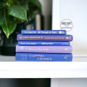 May include: A stack of five books with purple and blue covers. The titles of the books are "All Through the Night" by Mary Higgins Clark, "Master Your Metabolism" by Jillian Michaels, "Hotel of the Saints" by Ursula Hegi, "Between You & Me" by Susan Wiggs, and "Capital Crimes" by Stuart Woods. The top book has a sticker that says "Free Gift with purchase."