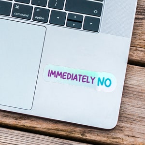 May include: A silver laptop computer with a sticker that says "IMMEDIATELY NO" on the top right corner of the trackpad.