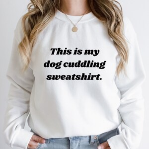 May include: White sweatshirt with black text that reads "This is my dog cuddling sweatshirt."