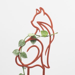 May include: A terracotta-coloured metal cat silhouette plant stand with a trailing vine growing through it.
