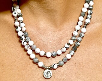 May include: A double-strand necklace made of white and gray beads with a silver Om charm pendant.